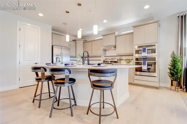 a kitchen with stainless steel appliances kitchen island granite countertop a table chairs sink and cabinets