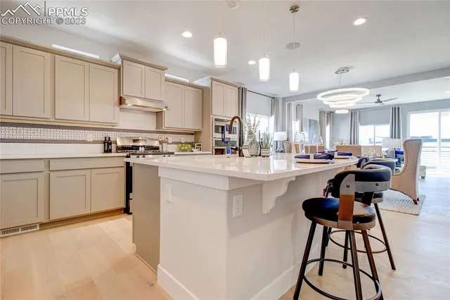 a kitchen with stainless steel appliances kitchen island granite countertop a stove a sink a refrigerator and white cabinets with wooden floor