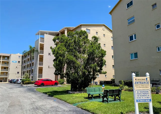 a front view of multi story residential apartment building with yard and sign board