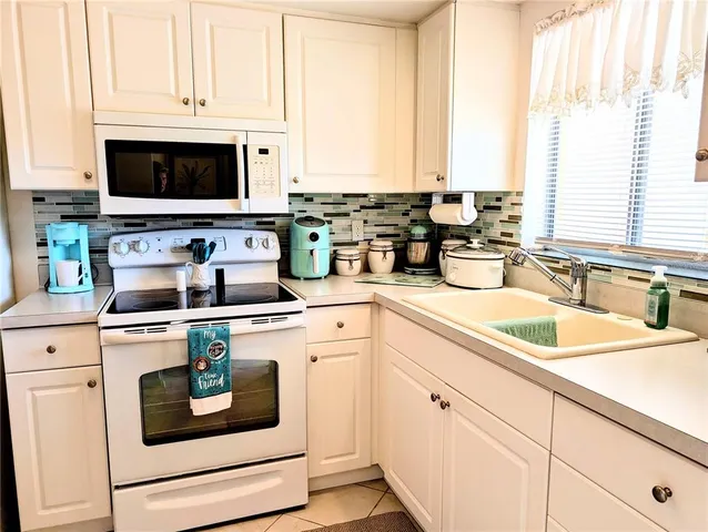 a kitchen with white cabinets and white appliances