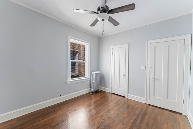 4820 West Wolfram Street, Unit 2 Chicago, IL 60641 - Photo 15 of 17 an empty room with wooden floor chandelier fan and windows