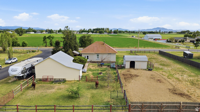 5264 West 5500th Street South Hooper, UT 84315 - Photo 5 of 38 Property featuring a main residence with a prominent gabled roof, a large detached auxiliary building, fenced pasture areas, an additional outbuilding, and expansive surrounding agricultural fields