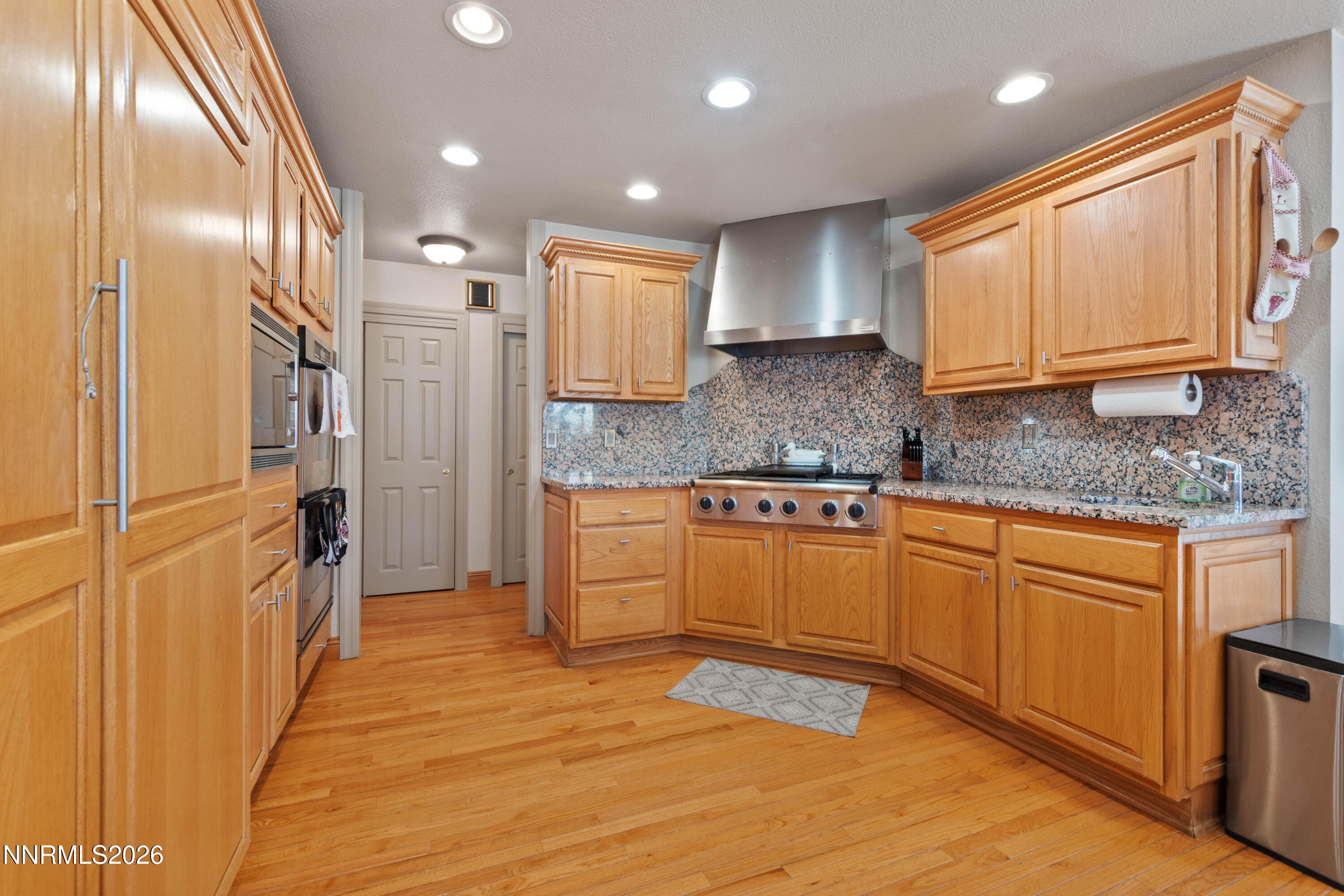 480 Duck Hill Road Washoe Valley, NV 89704 - Photo 5 of 27 a kitchen with stainless steel appliances granite countertop a refrigerator a sink dishwasher and wooden cabinets with wooden floor