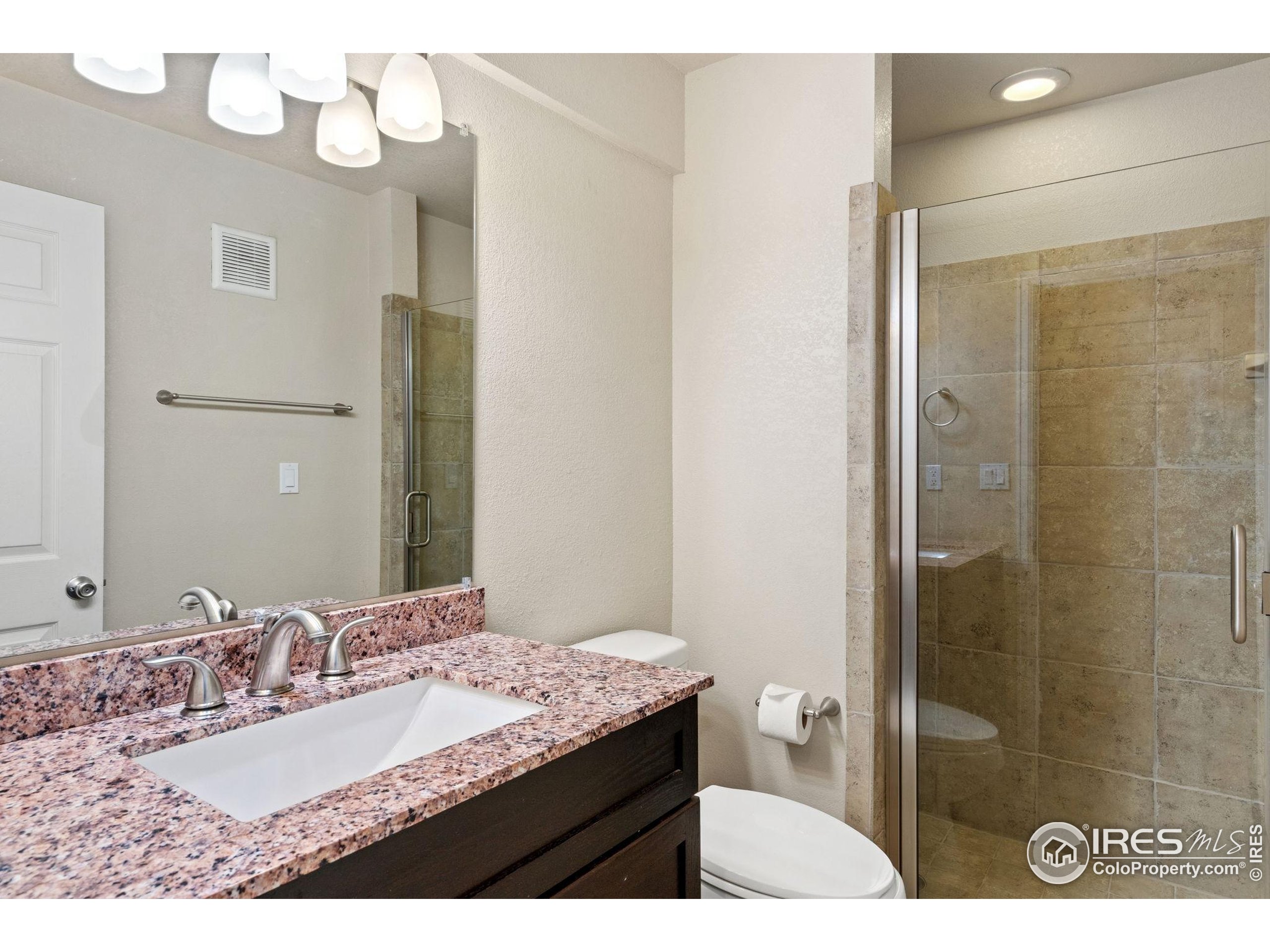 6612 Avondale Road, Unit 2B Fort Collins, CO 80525 - Photo 19 of 20 a bathroom with a granite countertop sink a toilet and a mirror