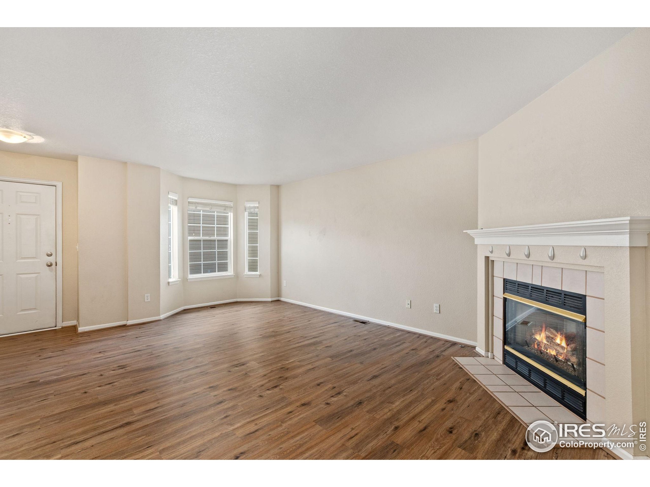 6612 Avondale Road, Unit 2B Fort Collins, CO 80525 - Photo 3 of 20 a view of an empty room with wooden floor fireplace and a window