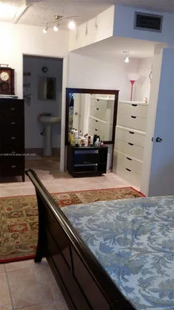 a bedroom with a bed and a lamp on dresser