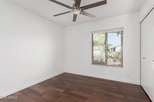 an empty room with wooden floor ceiling fan and windows