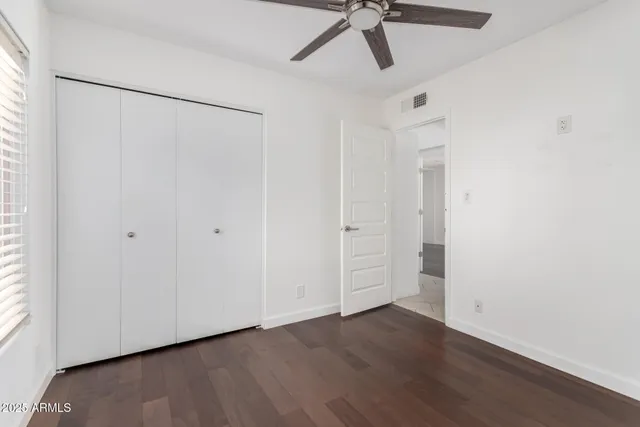 a view of empty room with wooden floor and fan