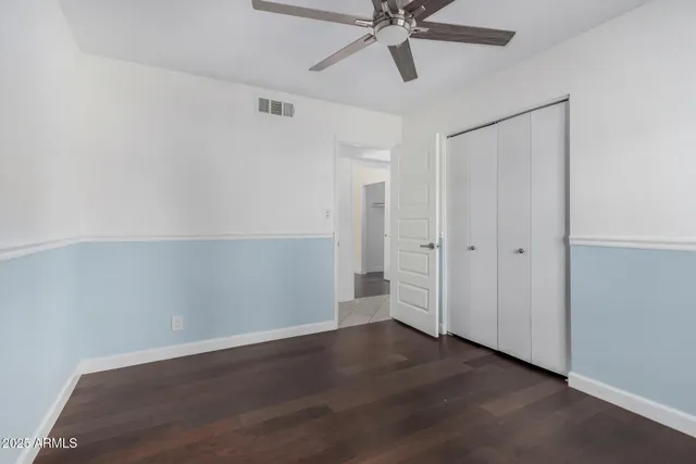 an empty room with wooden floor closet and fan