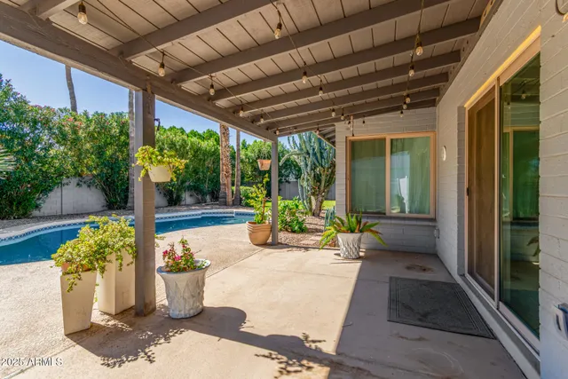 a view of a patio with table and chairs potted plants and floor to ceiling window and potted plants