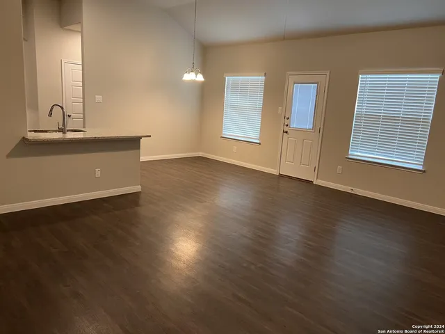 a view of an empty room with window and wooden floor