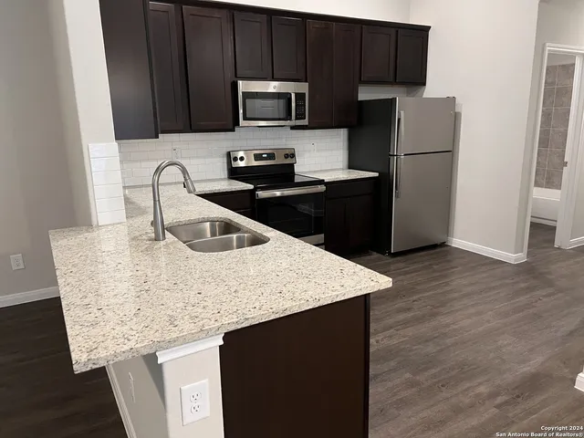 a kitchen with granite countertop a refrigerator and a sink