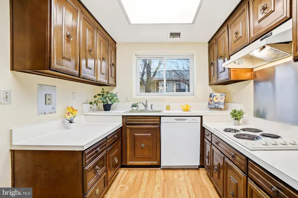 a kitchen with a sink a stove cabinets and a wooden floor