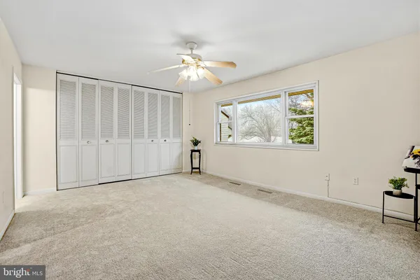 an empty room with windows and fan