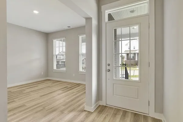 a view of an empty room with wooden floor and a window