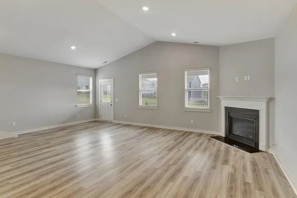 an empty room with windows and fireplace