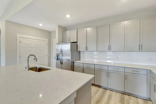 a kitchen with stainless steel appliances a sink dishwasher a refrigerator with white cabinets and wooden floor