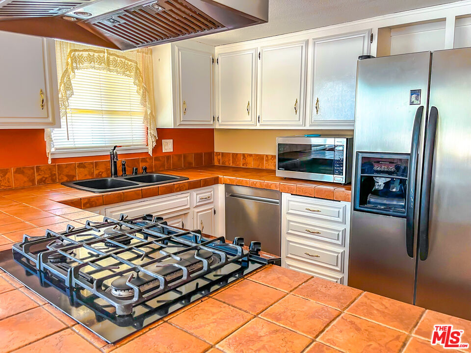 1001 South McCall Street Ridgecrest, CA 93555 - Photo 8 of 27 a kitchen with stainless steel appliances a stove a sink and a refrigerator