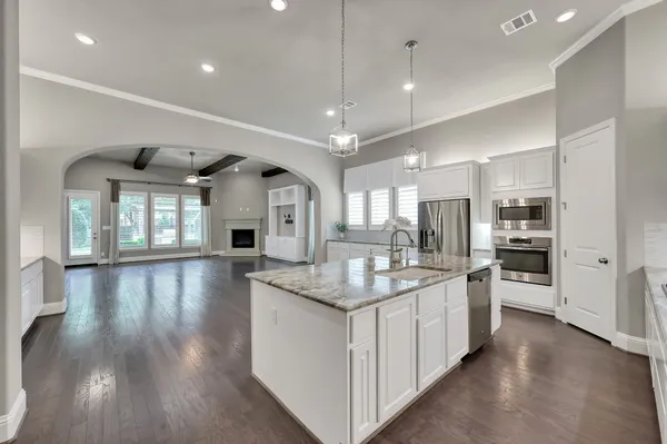 a kitchen with stainless steel appliances granite countertop a sink stove refrigerator and cabinets