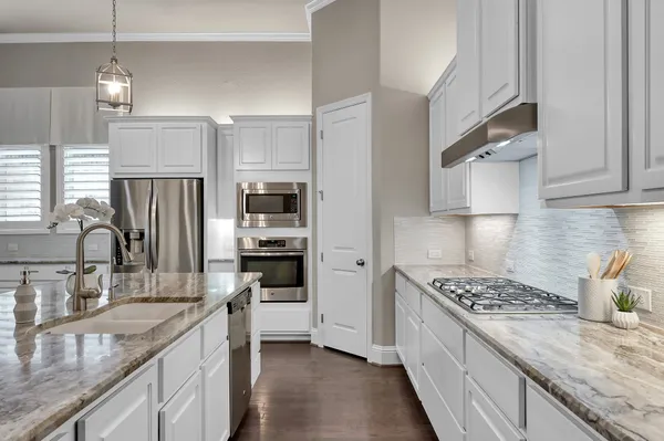 a large white kitchen with a white countertops a stove a sink and a refrigerator