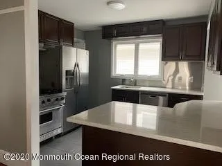 a kitchen with stainless steel appliances granite countertop a sink a stove a refrigerator cabinets and a counter top space