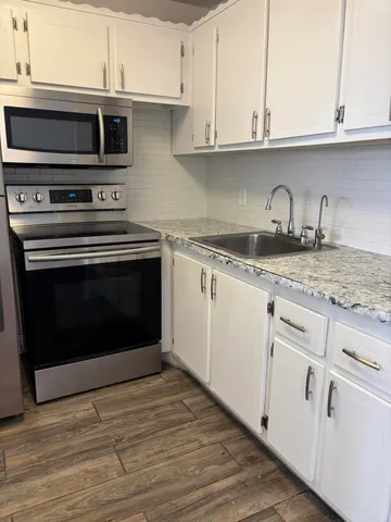 a kitchen with granite countertop a stove microwave and sink