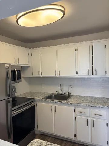 a kitchen with granite countertop a sink a stove and cabinets