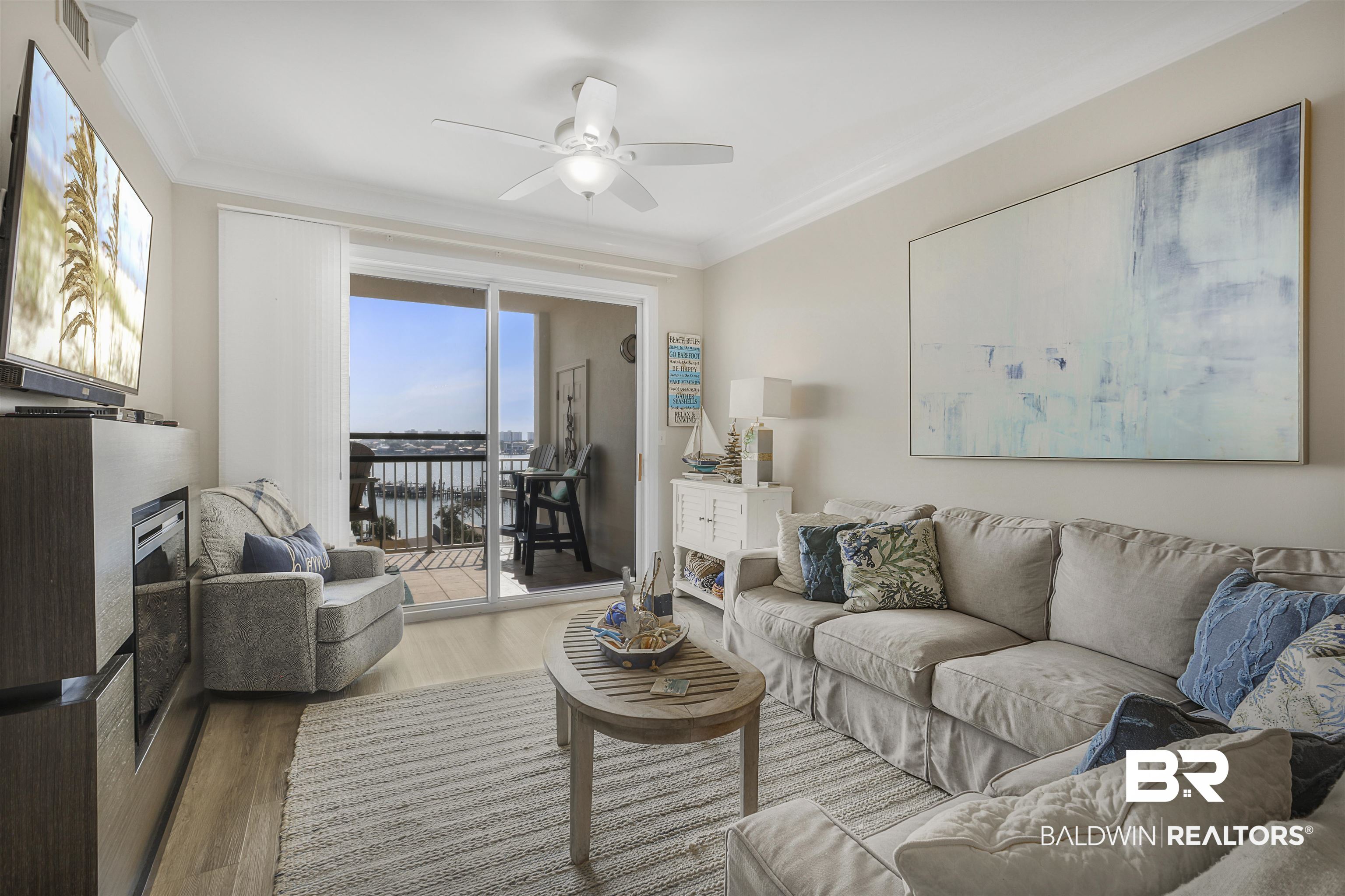 Living room with wood finished floors, ceiling fan, ornamental molding, and a fireplace