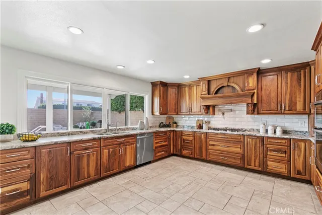 a large kitchen with stainless steel appliances granite countertop a stove sink and cabinets