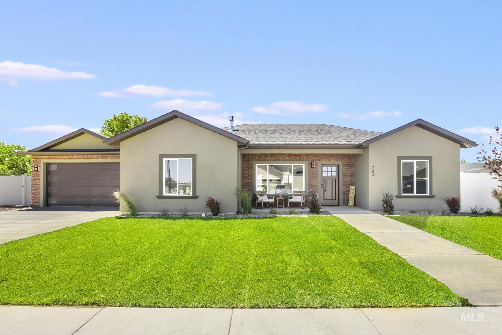 284 Sandi Road Twin Falls, ID 83301 - Photo 32 of 33 Modern single-story residence featuring a two-car garage with a contemporary door, a concrete driveway, brick and stucco exterior finishes, and a manicured lawn