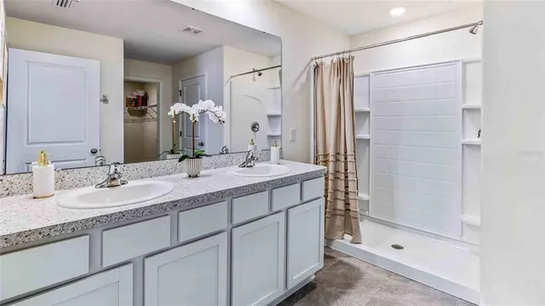 a bathroom with a double vanity sink mirror and shower