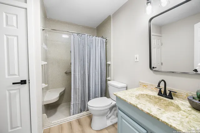 a bathroom with a granite countertop sink toilet and shower