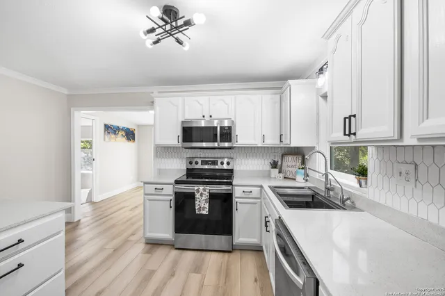 a kitchen with stainless steel appliances granite countertop a stove top oven a sink dishwasher and a refrigerator with wooden floor