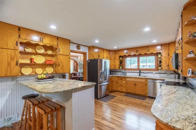 a kitchen with stainless steel appliances granite countertop a refrigerator a sink a stove and island