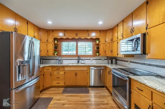 a large kitchen with stainless steel appliances granite countertop a stove and a sink
