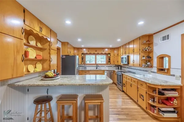 a open kitchen with stainless steel appliances wooden floor dining table and chairs