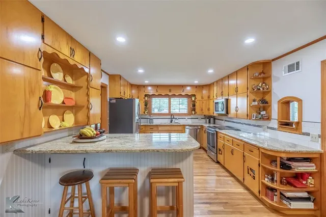 a open kitchen with stainless steel appliances wooden floor dining table and chairs