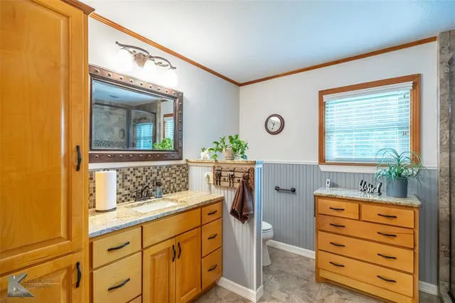 a bathroom with a granite countertop sink mirror vanity and next to a window
