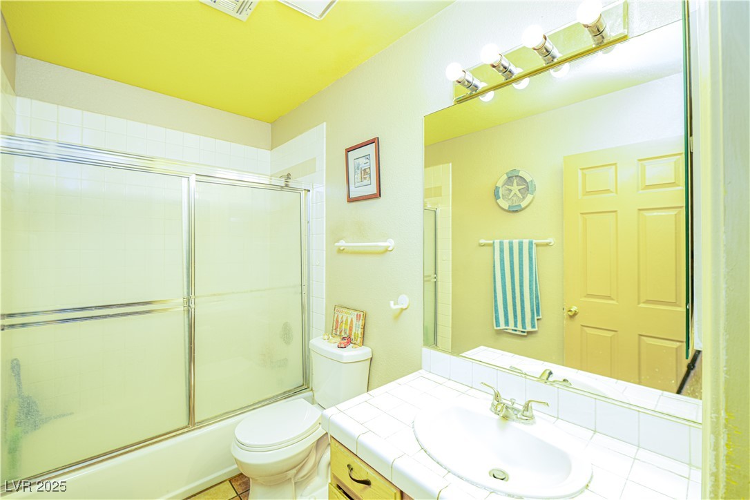 475 East Robindale Road Las Vegas, NV 89123 - Photo 17 of 41 Full bathroom featuring toilet, vanity, and bath / shower combo with glass door