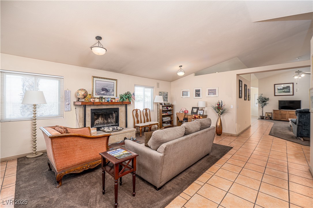 475 East Robindale Road Las Vegas, NV 89123 - Photo 3 of 41 Living room with a tile fireplace, light tile patterned flooring, vaulted ceiling, ceiling fan, and baseboards