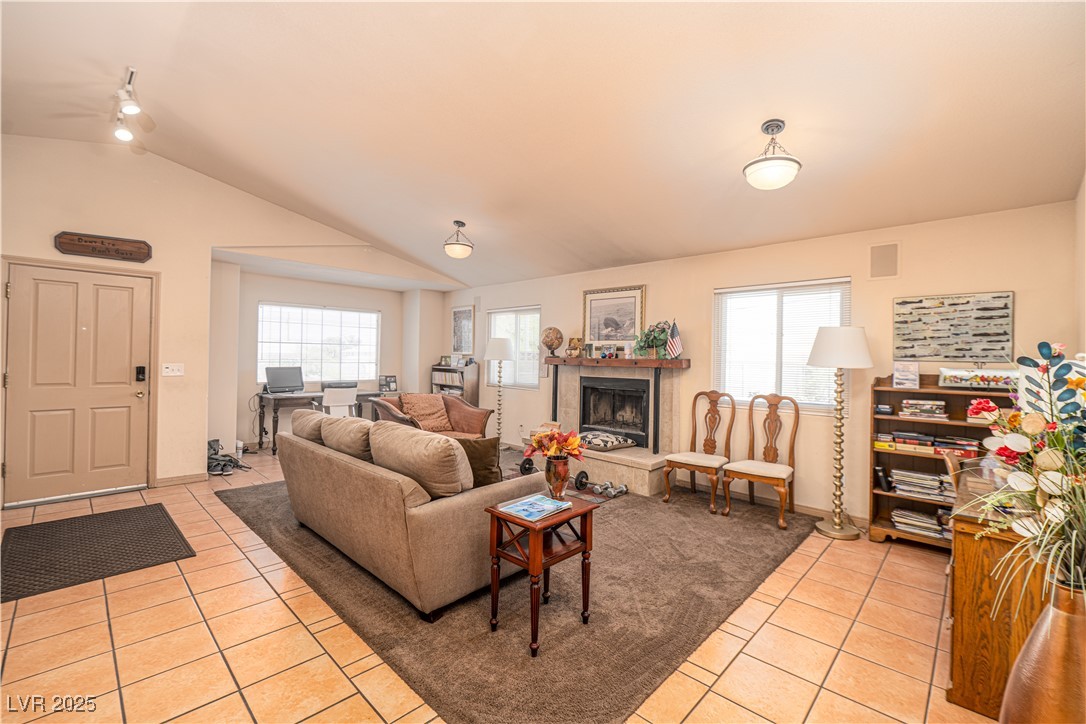 475 East Robindale Road Las Vegas, NV 89123 - Photo 38 of 41 Living room featuring light tile patterned flooring, healthy amount of natural light, vaulted ceiling, a fireplace with raised hearth, and a ceiling fan