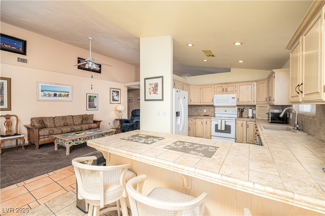 475 East Robindale Road Las Vegas, NV 89123 - Photo 39 of 41 Kitchen featuring white appliances, vaulted ceiling, a sink, open floor plan, and a peninsula