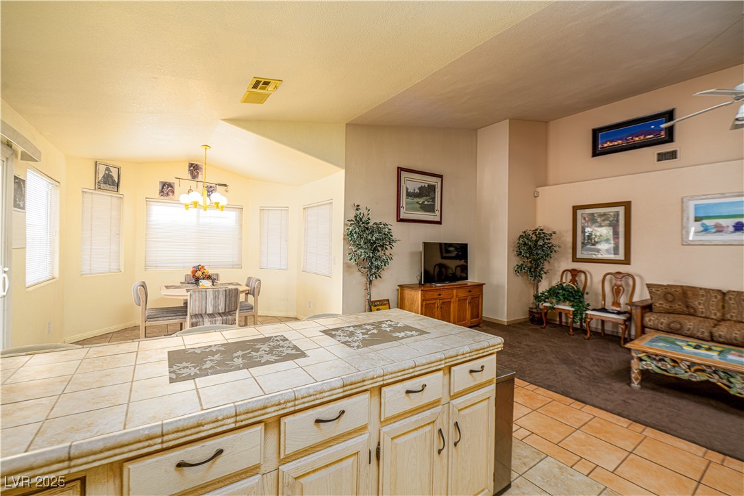 475 East Robindale Road Las Vegas, NV 89123 - Photo 40 of 41 Kitchen with tile counters, a chandelier, light carpet, open floor plan, and lofted ceiling
