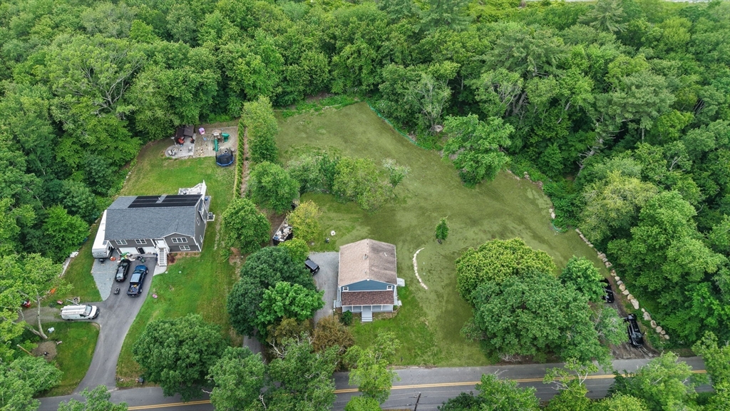 an aerial view of a house with a yard and covered with trees