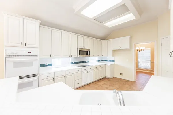 a kitchen with granite countertop a sink appliances cabinets and a counter top space