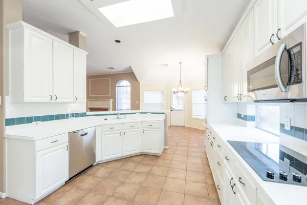 a large white kitchen with stainless steel appliances granite countertop a sink and dishwasher a stove top oven with white cabinets