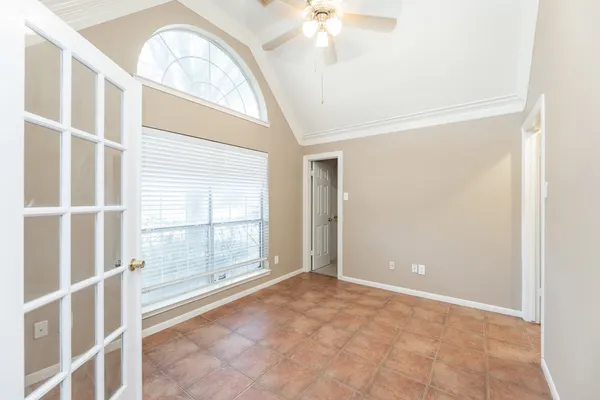 an empty room with a chandelier fan and windows