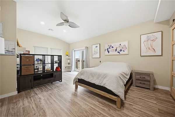 a spacious bedroom with a bed and a flat tv screen on the dresser
