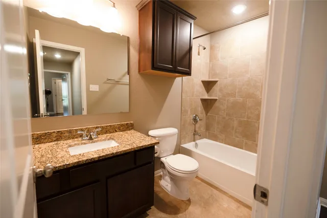 a bathroom with a granite countertop sink toilet mirror and bathtub