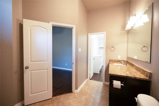 a en suite bathroom with a granite countertop sink and a mirror